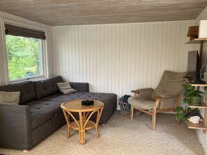 A cozy living room with a grey sofa, a round wooden table, and a wooden chair.