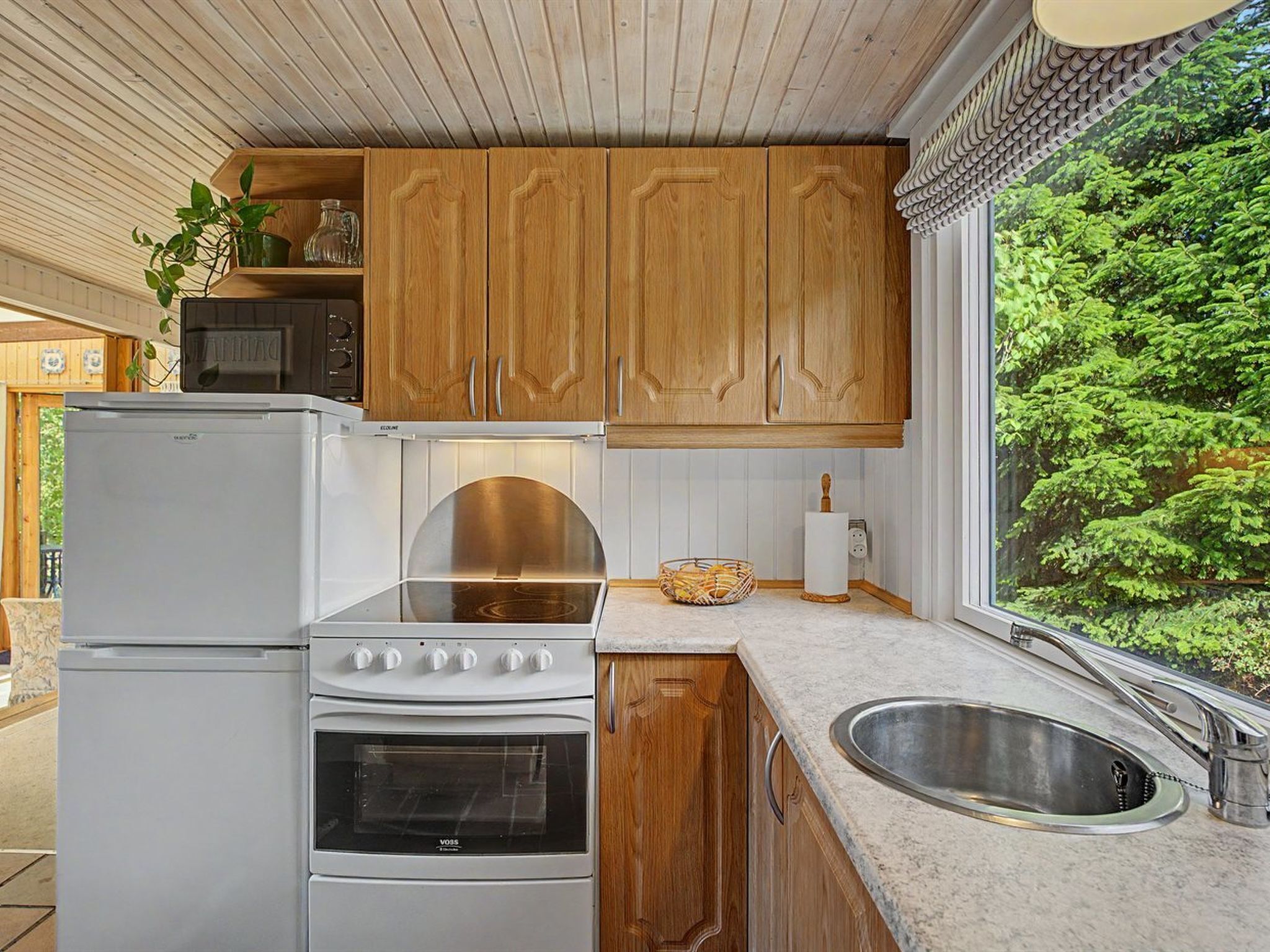 A kitchen with wooden cabinets, a white refrigerator, a stove, and a sink.