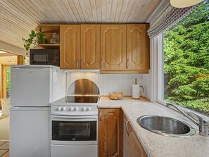 A kitchen with wooden cabinets, a white refrigerator, a stove, and a sink.