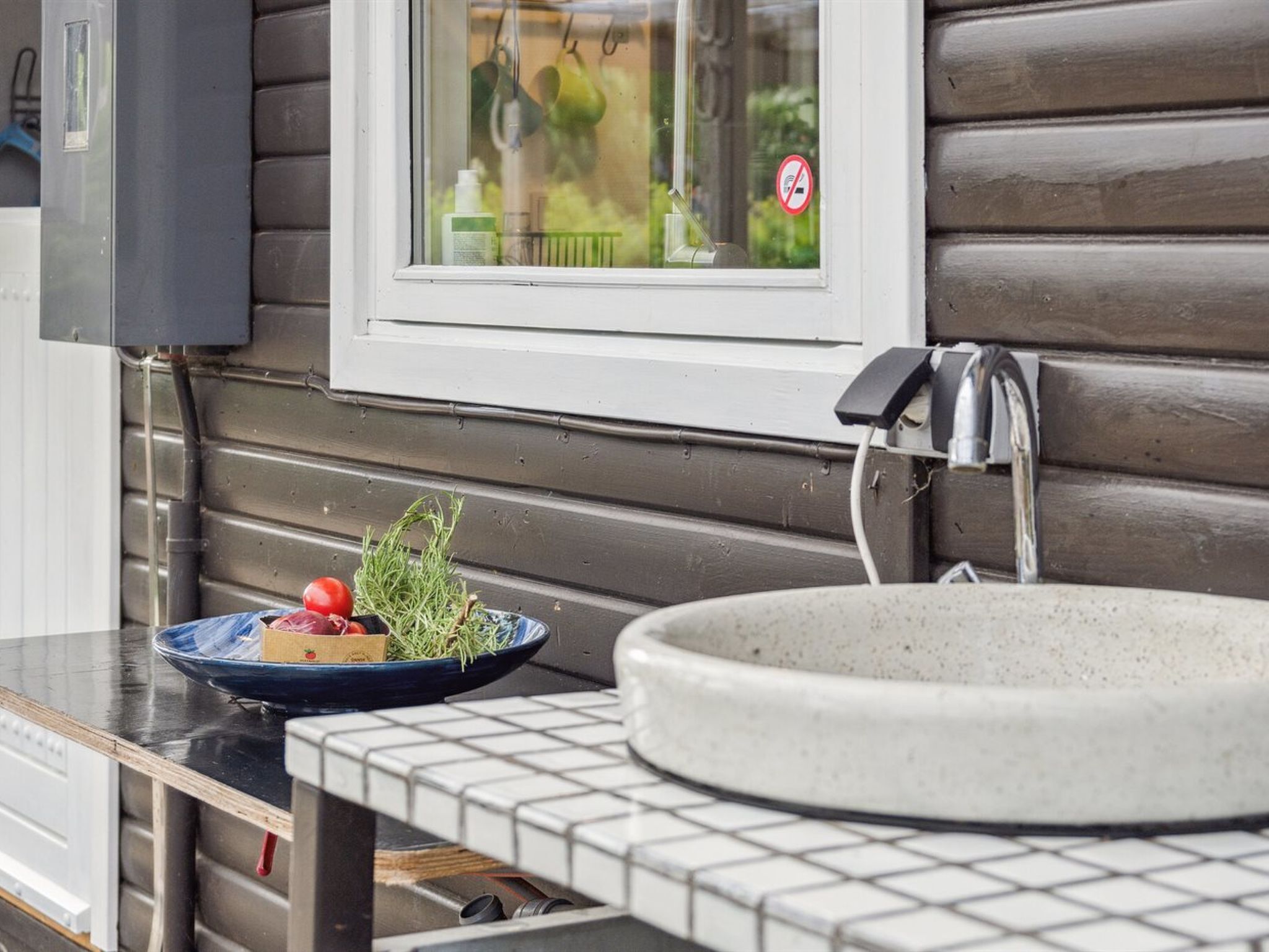 Une salle de bain avec un lavabo, une fenêtre donnant sur un espace verdoyant et un porte-serviettes.