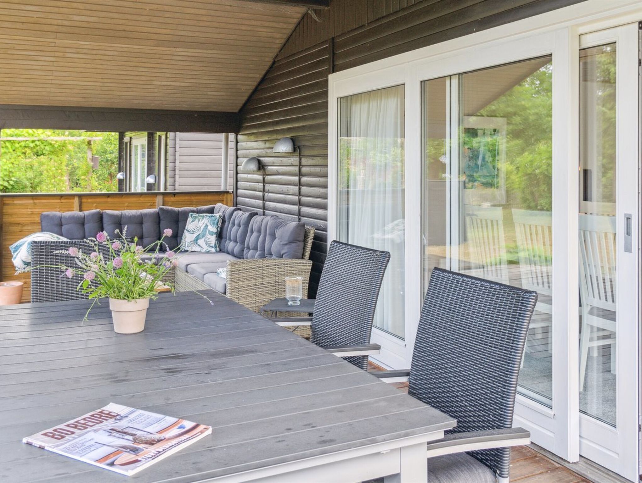 A covered outdoor seating area with a table, chairs, and a sofa.