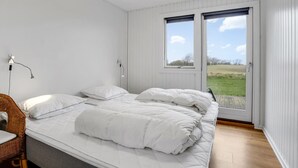 Une chambre à coucher avec un lit, une chaise et une fenêtre donnant sur un champ.