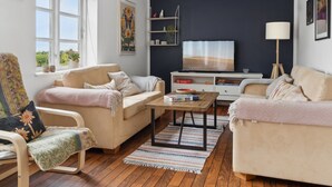 Ein Wohnzimmer mit zwei Sofas, einem Couchtisch, einem Fernseher und einem Bücherregal.