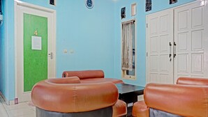 A room with a green door marked with the number 4, a white door, and a large white wardrobe. There are two brown leather sofas and a small table in the center. - Hotel O Fajar Inn (Depok)
