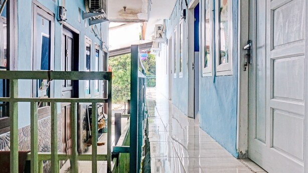 A corridor with blue walls, white doors, and a tiled floor. - Hotel O Fajar Inn (Depok)