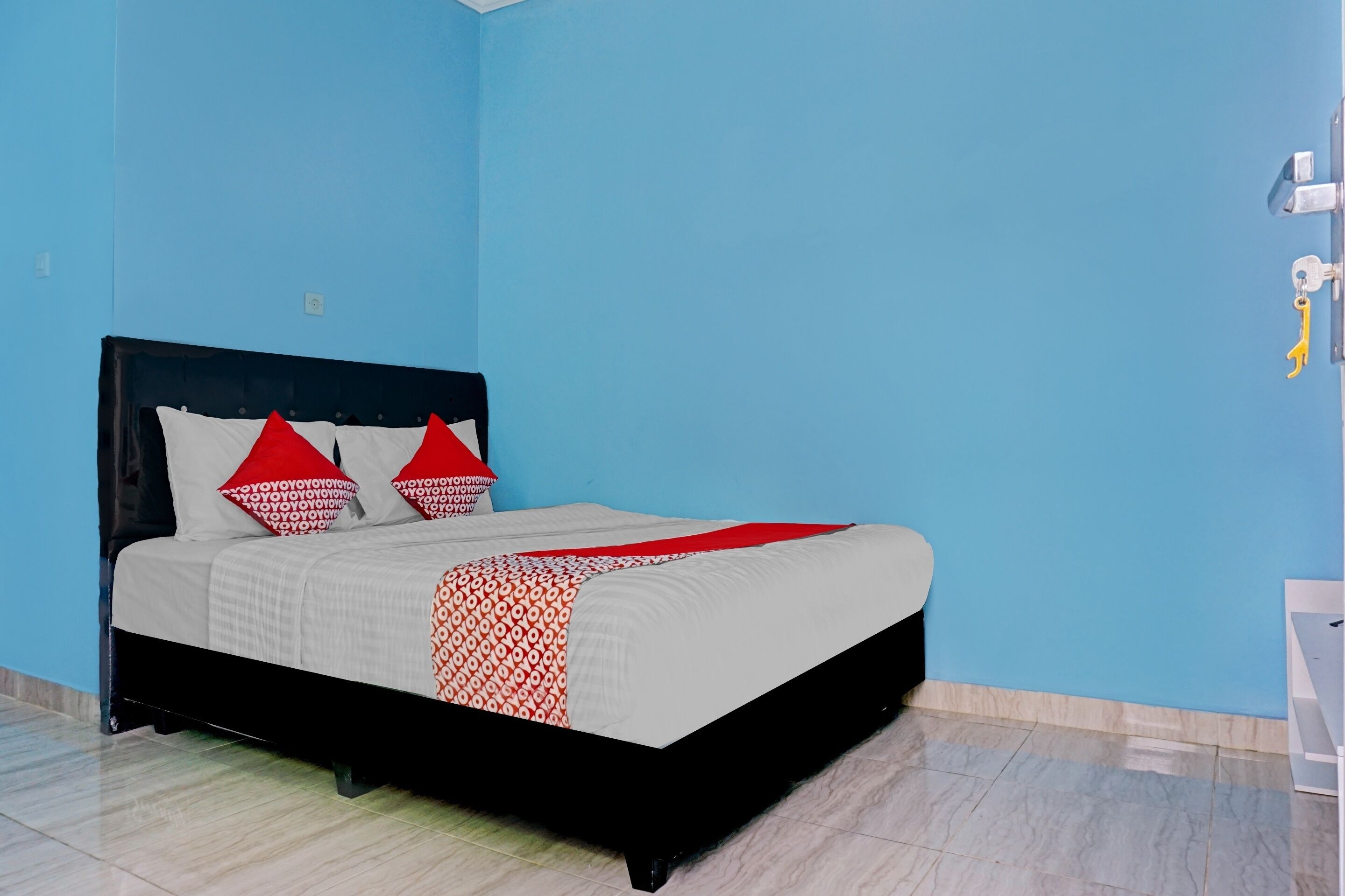 A bed with a black frame, white bedding, and red and white pillows.