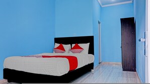A bedroom with a bed, blue walls, and a door. - Hotel O Fajar Inn (Depok)