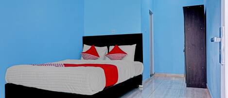 A bedroom with a bed, blue walls, and a door.
