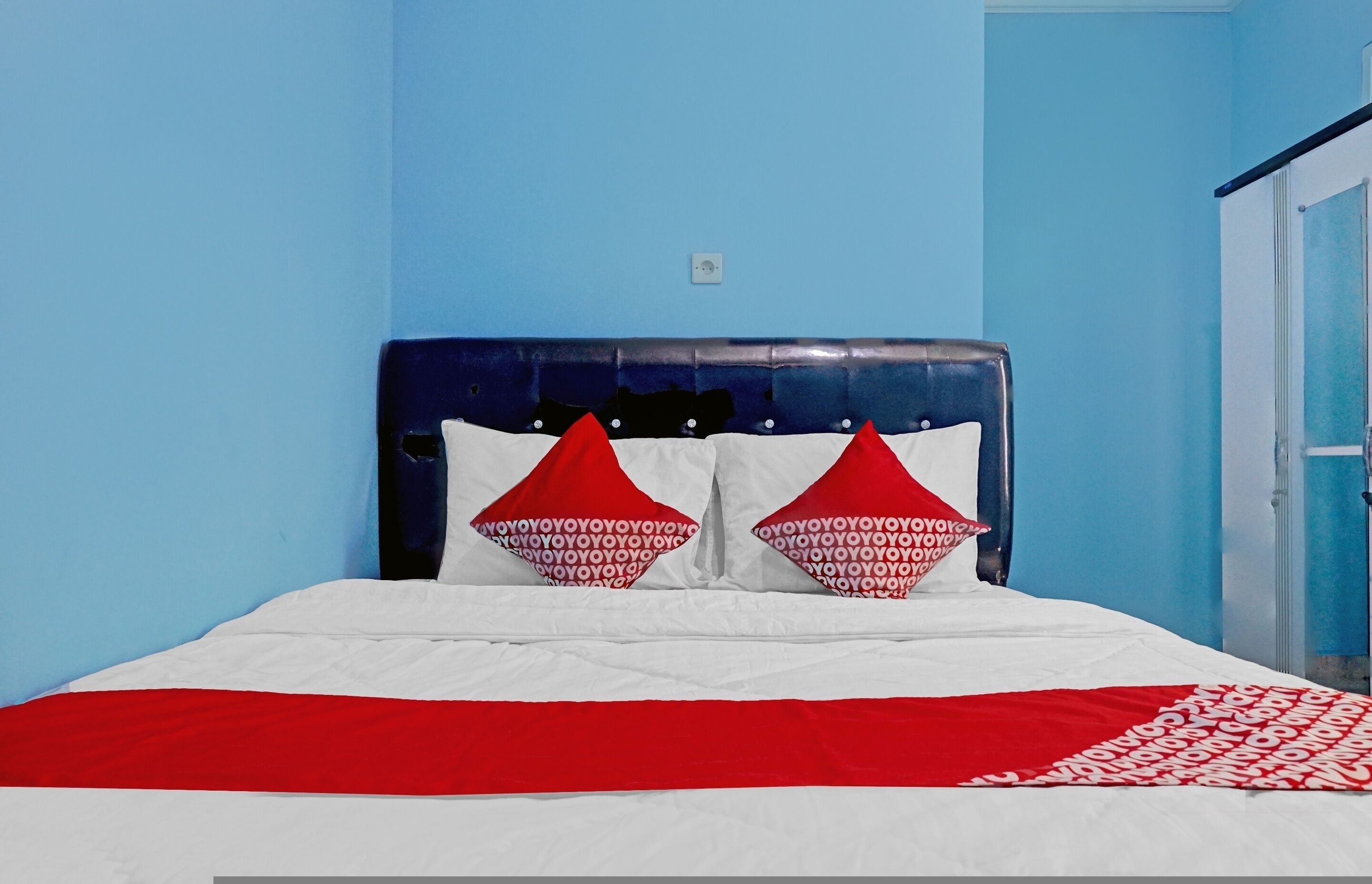 A bed with a white and red bedspread, two red pillows with white text, and a dark headboard.
