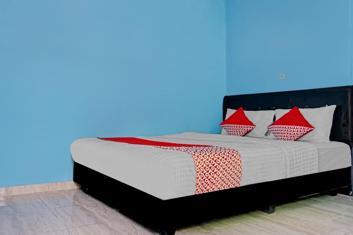 A bed with a black frame, white bedding, and red pillows.