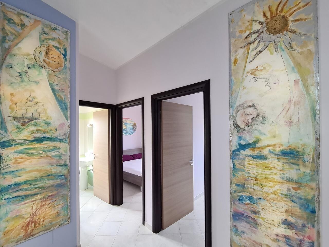 Un couloir avec deux portes donnant sur une chambre à coucher équipée d’un lit et d’une table de chevet.