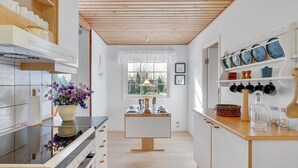 A modern kitchen with wooden beams, white cabinetry, and a central island.