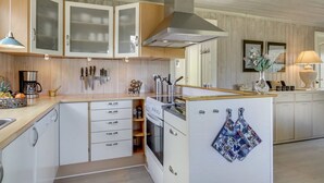 Une cuisine moderne avec des meubles blancs, une hotte en acier inoxydable et un plan de travail en bois.