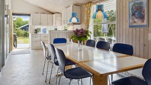 A modern kitchen with wooden cabinets, a dining area with a table and chairs, and a view of the outdoors. - "Eini" - 500m from the sea by Interhome (Væggerløse)