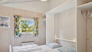 A bedroom with two beds, a window with curtains, a radiator, and a wardrobe. - "Eini" - 500m from the sea by Interhome (Væggerløse)