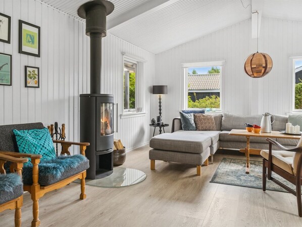 A modern living room with a wood-burning stove, a sofa, a coffee table, and a dining table.