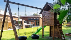 A wooden swing set with tire swings, a slide, and a climbing structure in a backyard. - "Bjarka" - 700m from the sea by Interhome (Væggerløse)