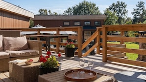An outdoor deck with wicker furniture, a wooden staircase, and a large umbrella. - "Bjarka" - 700m from the sea by Interhome (Væggerløse)