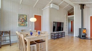 A spacious living room with a wooden floor, a dining area with a table and chairs, a fireplace, and a television.