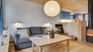 Una sala de estar acogedora con un sofá, una mesa de centro de madera, una lámpara colgante y una chimenea.