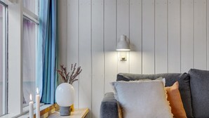 Una sala moderna con un sofá gris, una mesita con velas y un florero con plantas secas.