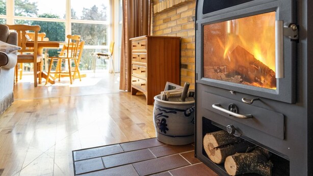 A cozy living room with a fireplace, wooden furniture, and a large window. - "Sanna" - 330m from the sea by Interhome (Væggerløse)