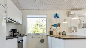 A modern kitchen with white cabinetry, a large window, and a hanging light fixture.