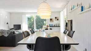 A modern dining area with a large table, black chairs, and a unique pendant light.