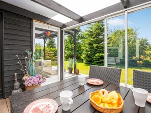 A modern outdoor dining area with a table set for two, surrounded by wicker chairs, and a view of a lush garden. - "Gabi" - 700m from the sea by Interhome (Væggerløse)