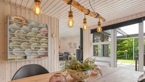 Un coin repas avec une table en bois, un vase avec des plantes et un porte-assiettes fixé au mur.