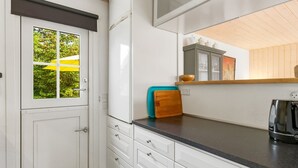 Une cuisine moderne avec des meubles blancs, un plan de travail noir et une bouilloire en acier inoxydable.