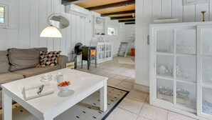 Un salón acogedor con sofá, mesa de centro y chimenea. Se ve una escalera que sube a un nivel superior.