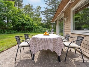 Relax in style with a round table and four comfortable chairs, surrounded by lush greenery.