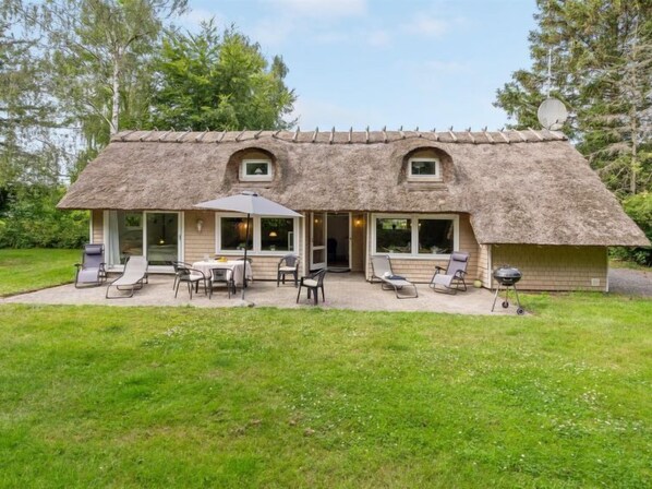 Relax in a cozy cottage with a spacious patio area, complete with lounge chairs and a table.