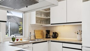 A modern kitchen with white cabinets, a black countertop, a stove, and a window overlooking a deck. - "Hallveig" - 1.1km from the sea by Interhome (Væggerløse)