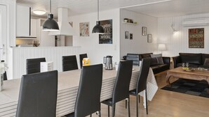 A modern living room with a dining area, featuring a large table, black chairs, a sofa, and a coffee table. - "Hallveig" - 1.1km from the sea by Interhome (Væggerløse)