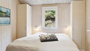 A bedroom with a bed, a window, and wooden walls. - "Hallveig" - 1.1km from the sea by Interhome (Væggerløse)