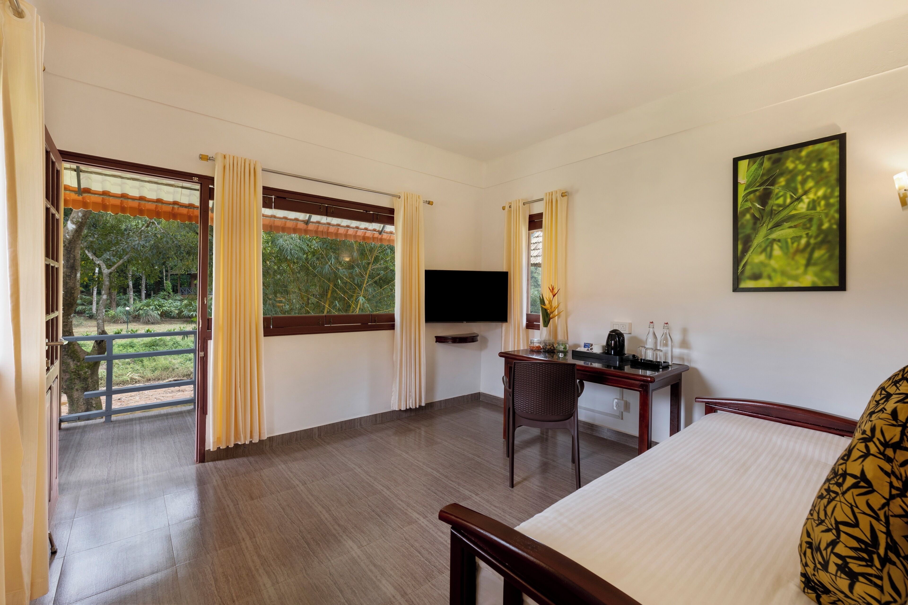 A hotel room with a bed, a desk with a chair, a TV, and a window with curtains.