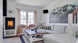 Ein gemütliches Wohnzimmer mit Kamin, einer Couch, einem Couchtisch und einem Gemälde an der Wand.