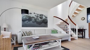 Ein modernes Wohnzimmer mit einem weißen Sofa, einem Holztisch und einer Treppe mit weißen Geländern.
