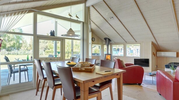 Ein geräumiger Wohnbereich mit Holzboden, Kamin, einem Esstisch mit Stühlen und einem roten Sofa.