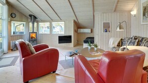 Ein gemütliches Wohnzimmer mit Kamin, Ledersofas, Fernseher und Holzboden.