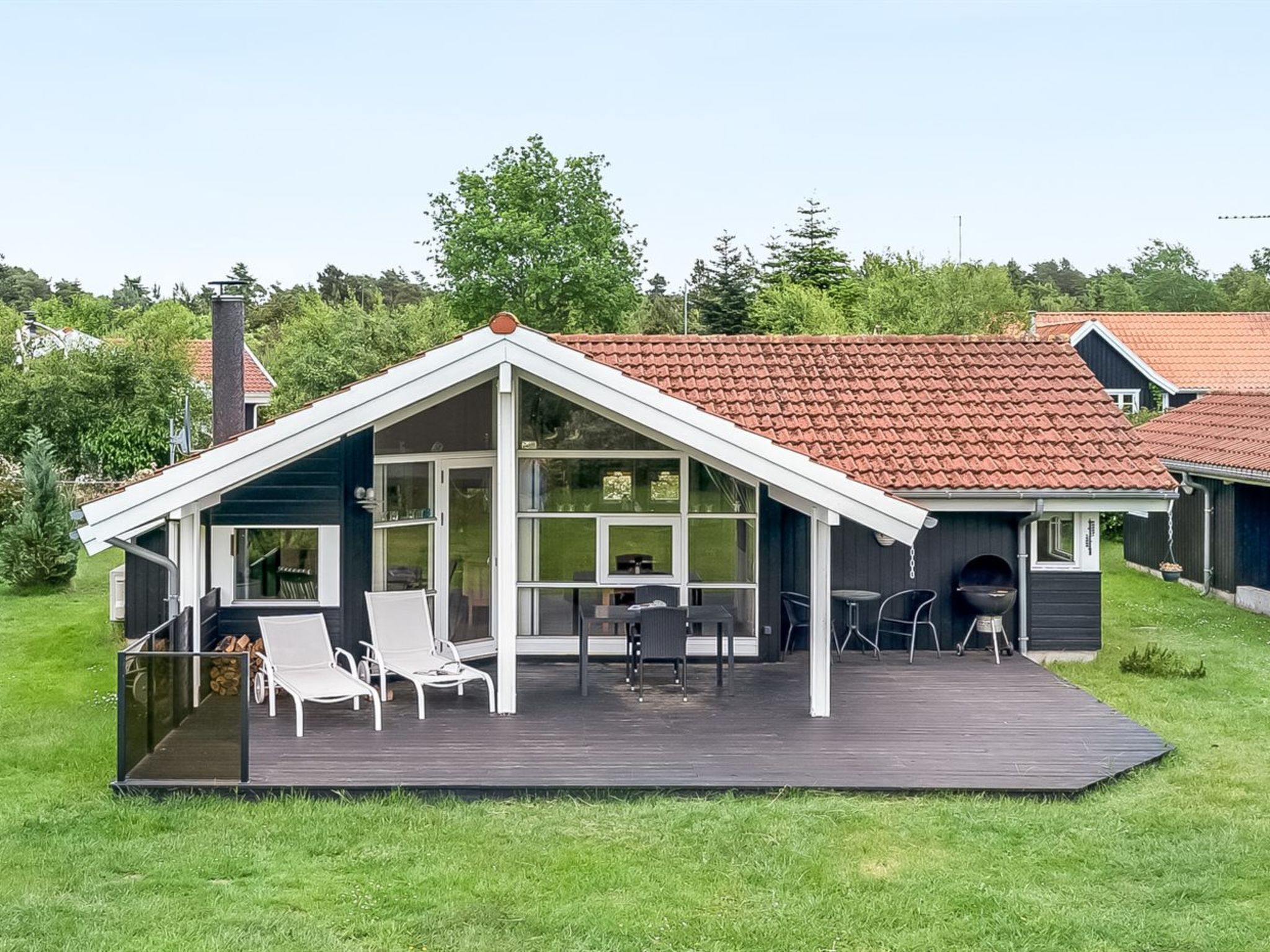 Et moderne hus med stor terrasse, overdækket patio og skorsten.