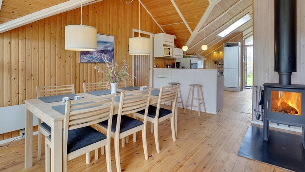 L’intérieur d’un chalet en bois chaleureux et accueillant, comprenant un coin repas, une cuisine et un poêle à bois.