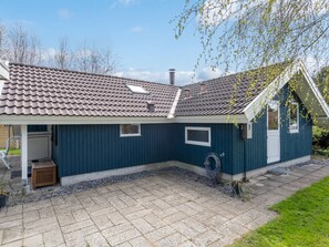 Ein einstöckiges Haus mit Ziegeldach, einer überdachten Veranda und einer kleinen angebauten Garage.