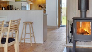 Une cuisine moderne avec un plancher en bois, un îlot central, des tabourets de bar et un poêle à bois.