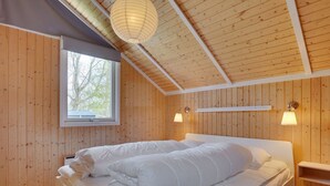 Une chambre confortable avec un plafond en bois, une grande fenêtre et deux lampes de chevet.