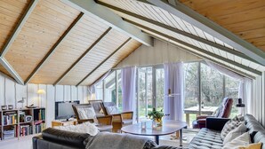 A modern living room with a high ceiling, large windows, a sofa, a coffee table, and a bookshelf.