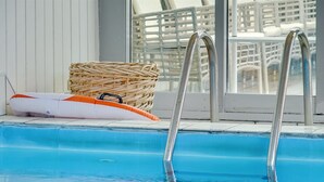 A swimming pool with metal ladders, a white inflatable float, and a wicker basket.