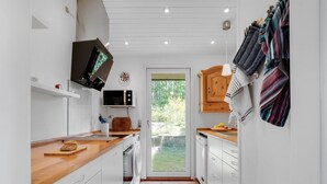 A modern kitchen with white cabinetry, a wooden countertop, and a built-in microwave. - "Miona" - 725m from the sea by Interhome (Kalundborg)